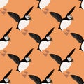 Cartoo seabird seamless pattern with hand drawn puffin birds silhouettes. Pastel orange background