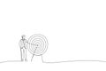 Cartoon of business man standing next to a huge target with a dart in the center, arrow in bullseye. Metaphor for reaching goals