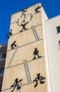 Cartoon figure climbing ladders on the facade of an apartment building in Magdeburg