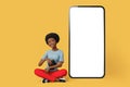 Smiling happy young afro american woman she sit near big huge blank screen mobile cell phone with workspace copy space mockup area Royalty Free Stock Photo