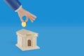 Cartoon hand putting a coin in a moneybox shaped like a bank building with bank text in spanish with copy space. 3d illustration