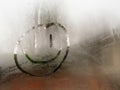 Cartoon happy smiley face drawn on a condensation covered window during the day time