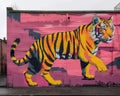 Cartoon-inspired animal murals in urban settings, Vibrant Tiger Mural on Urban Building Wall, A large, colorful mural of a tiger