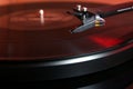 Cartridge of a modern high quality turntable record player about to be lowered onto a vinyl analogue music LP with red backlight. Royalty Free Stock Photo