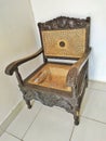 carved antique rattan chair n the corner, broken rattan seat Royalty Free Stock Photo