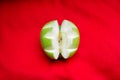 Carved apple on red background, close up / Green apple cut out decoratively / Fruits and vegetables healthy food Royalty Free Stock Photo