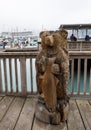 A carved bear holding a salmon on the boardwalk at the small boat harbour at Seward, Alaska with boats and cruise ship in