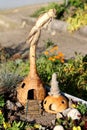 Carved dry squash made to look like two small houses with wooden stairs entrance surrounded with small decorative rocks and