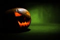 The carved face of pumpkin glowing on Halloween on green background Royalty Free Stock Photo
