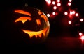 Carved face of pumpkin glowing on Halloween on red bokeh light background