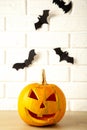 Carved glowing pumpkin and black bats on light background. Halloween celebration. Vertical foto
