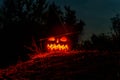 Carved halloween pumpkin jack-o-lantern wearing witch hat with burning candles glows in a darkness. Spooky landscape Royalty Free Stock Photo