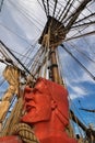 Carved head of sailor painted in orange red and rigging ropes of