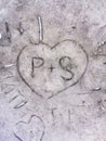 Carved love design in stone, heart with plus and letters on rock, carving, close uo, grey background