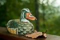 Carved and painted wood, decoy duck resting on a wood railing