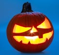 Carved pumpkin for Halloween jack-o\'-lanterns with scary smiles and burning candle inside isolated on blue background Royalty Free Stock Photo