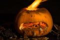 A carved pumpkin looks to be vomitting with fire erupting from i