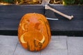 Carved pumpkin with scary face and ax, modern festive decoration of european street. Halloween street decor. Happy Halloween