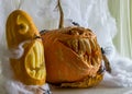 Carved pumpkin with a scary smile, spiders, white cobweb background, decoration and holiday concept, carved pumpkin for a fun