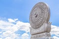 Carved sandstone Dharmachakra on blue sky background