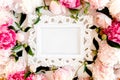 Carved, white frame decorated of beautiful pink peonies on white background. Flat lay, top view. Valentine`s background