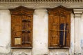 Carved windows with closed wooden shutters on the facade of a dilapidated old building Royalty Free Stock Photo