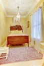 Carved wood bed with pillows in small yellow bedroom. Royalty Free Stock Photo