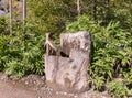 Carved wooden column for drinking mountain water with a Georgian cross on a mountain road in the mountainous part of Georgia