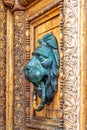 Carved wooden door with a green brass handle in the shape of a lion`s head Royalty Free Stock Photo