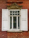A carved wooden window with shutters on the facade of an old brick building Royalty Free Stock Photo