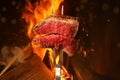 Carving fork with beef steak near bonfire