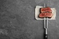 Carving fork with slices of delicious beef steak on table, top view. Space for text Royalty Free Stock Photo