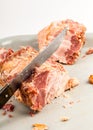 Carving a piece of tender pork roast with a sharp knife on a light background, exposing the succulent meat, object closeup, nobody Royalty Free Stock Photo