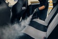 Carwash, worker cleans seats with steam cleaner Royalty Free Stock Photo