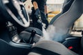 Carwash, worker cleans seats with steam cleaner Royalty Free Stock Photo