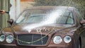 Carwash worker pouring expensive car with cleaning foam and caring about auto