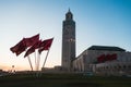 View of Hassan II mosque and a waving moroccan flags against sky