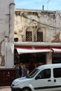 A street in Casablanca with a shabby house, a grocery store, and a white car