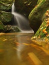 Cascade on small mountain stream, water is running over mossy sandstone boulders and bubbles create on level milky water. Royalty Free Stock Photo