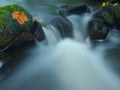 Cascade on small mountain stream, water is running over mossy sandstone boulders and bubbles create on level milky water. Royalty Free Stock Photo