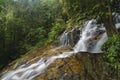 Cascading tropical waterfall. wet and mossy rock, surrounded by green rain forest Royalty Free Stock Photo