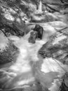 Cascading water swirling between rocks before flowing around and Royalty Free Stock Photo