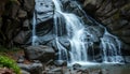 Cascading waterfall flows over dark, jagged rocks