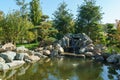 Cascading waterfall surrounded by topiary pine trees in Japanese garden of public landscape park of Krasnodar Royalty Free Stock Photo