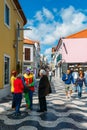 A man dressed up as a clown speaks to locals on a busy commercial street in the heart of Cascais, Portugal