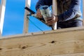 In this case, the builder uses an air hammer when nailing wooden beams for construction in the housing development. Royalty Free Stock Photo