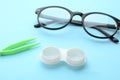 Case with contact lenses, glasses and tweezers on light blue background Royalty Free Stock Photo