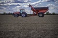 Case IH tractor and an Unverferth grain cart rest in a completely harvested field