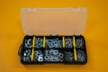 Case organizer with screws, nuts and washers on a yellow background.