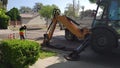 A CASE 590 Super N Backhoe Loader digs a trench at a construction site, lifting asphalt pieces